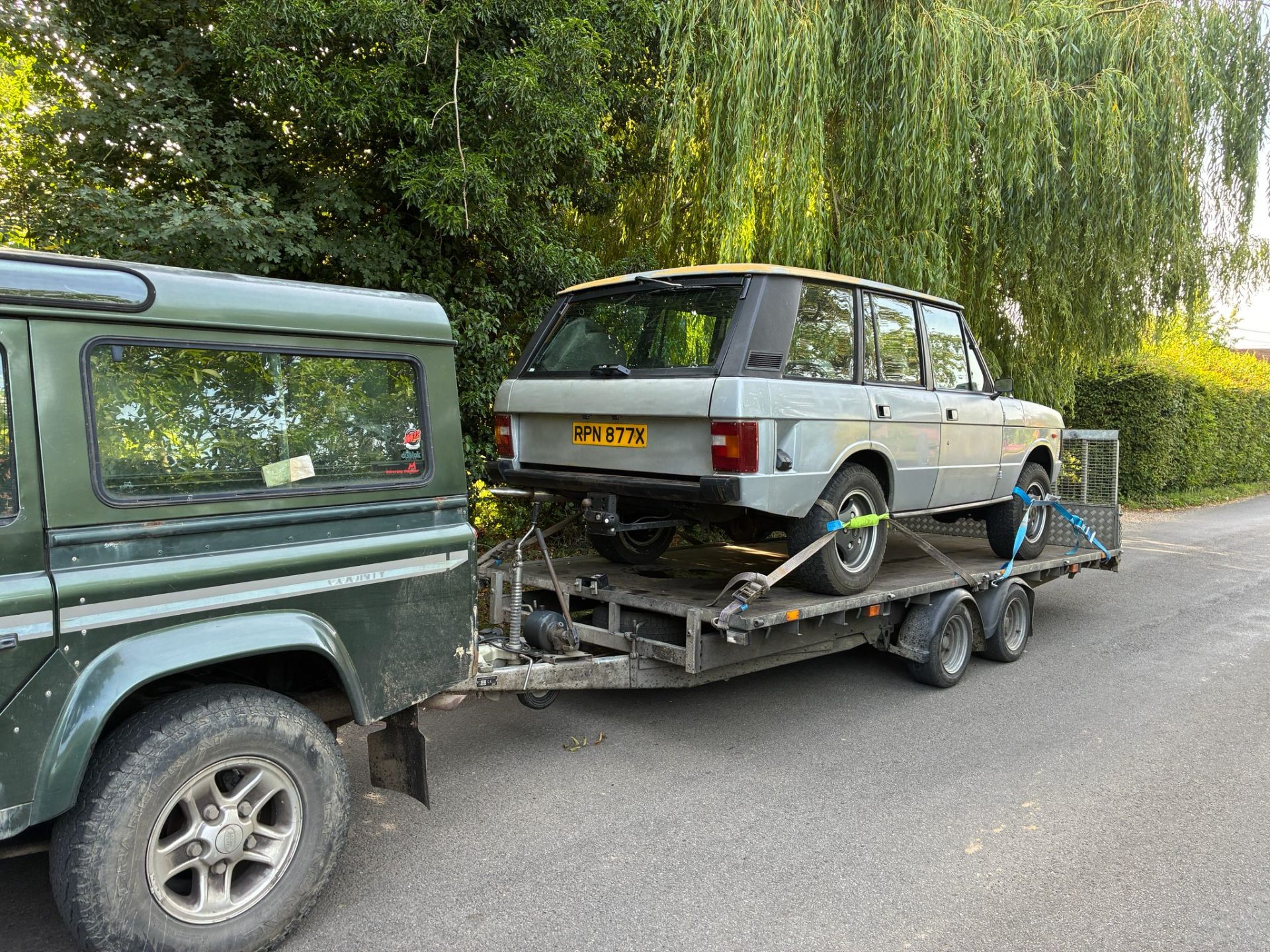 Classic Range Rover loaded on a trailer behind a Defender